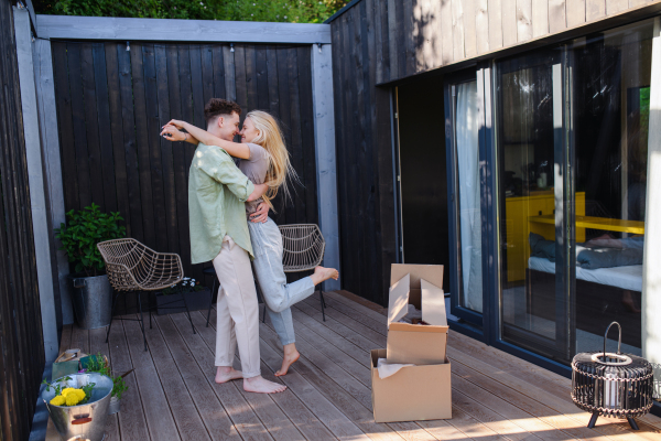 A cheerful young couple moving in their new tiny house in woods. Conception of moving and sustainable living.