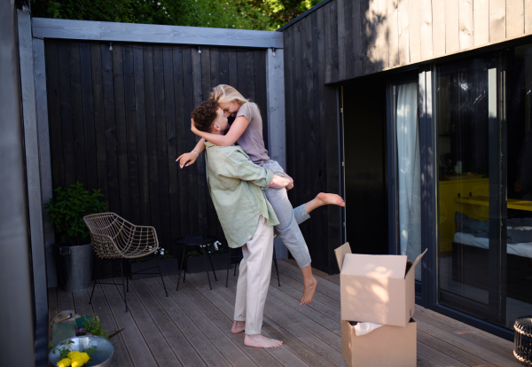 A cheerful young couple moving in their new tiny house in woods. Conception of moving and sustainable living.