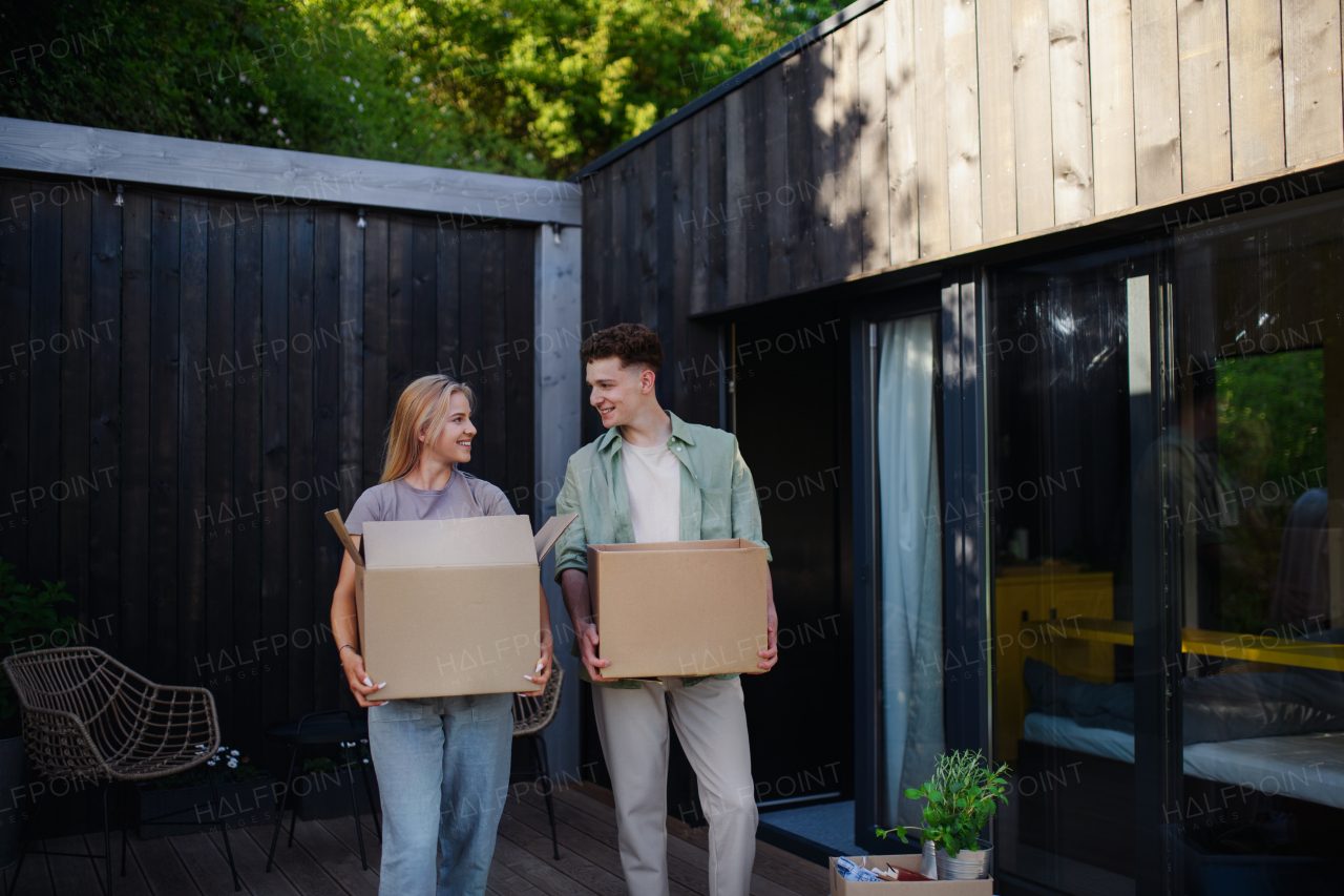 A cheerful young couple moving in their new tiny house in woods. Conception of moving and sustainable living.