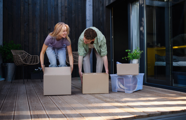 A cheerful young couple moving in their new tiny house in woods. Conception of moving and sustainable living.