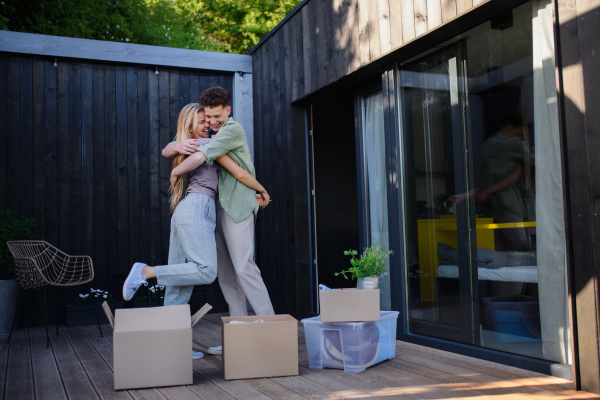 A cheerful young couple moving in their new tiny house in woods. Conception of moving and sustainable living.