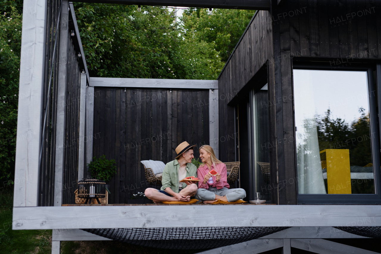 Cheerful young couple in love eating a watermelon together at terrace.