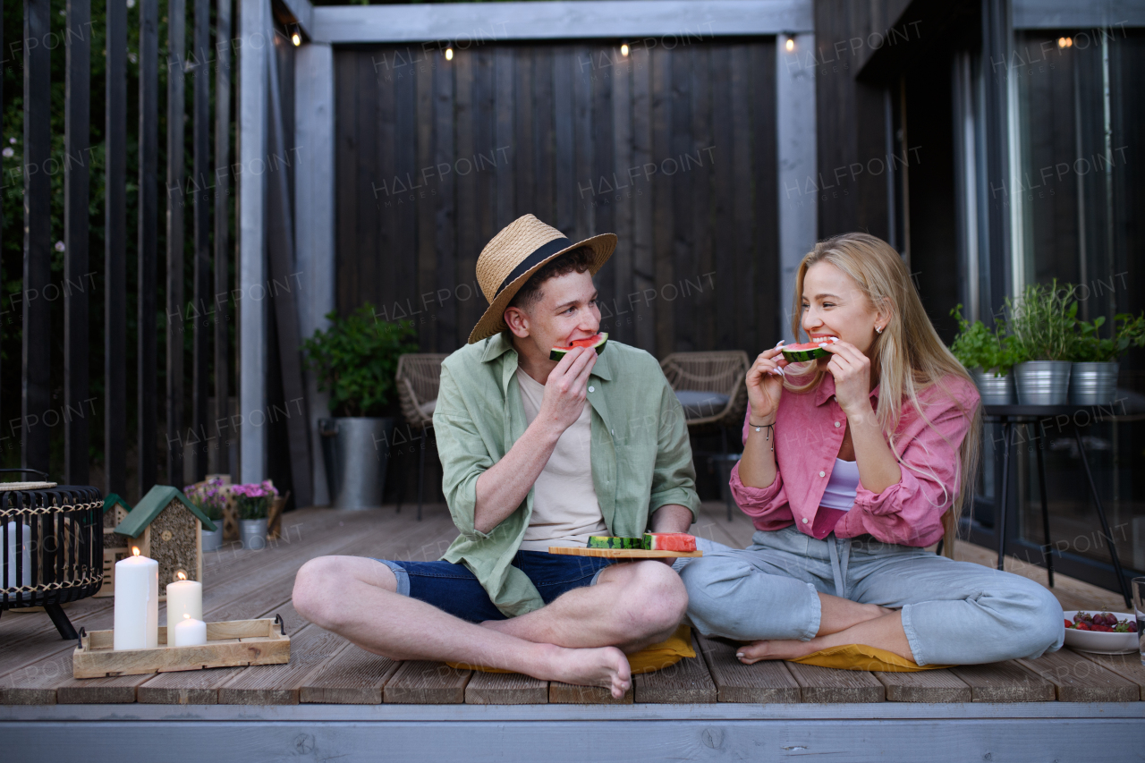 A cheerful young couple in love eating slice of watermelon together