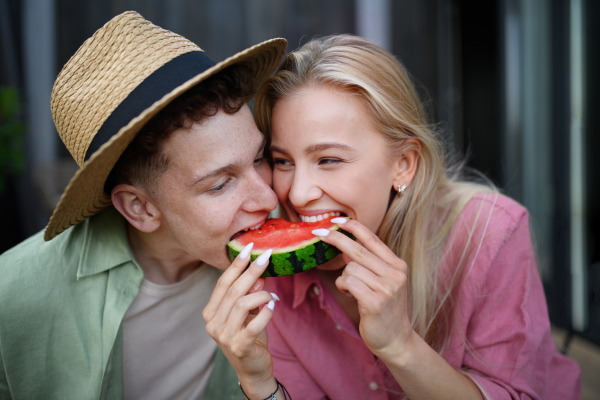 A cheerful young couple in love eating slice of watermelon together