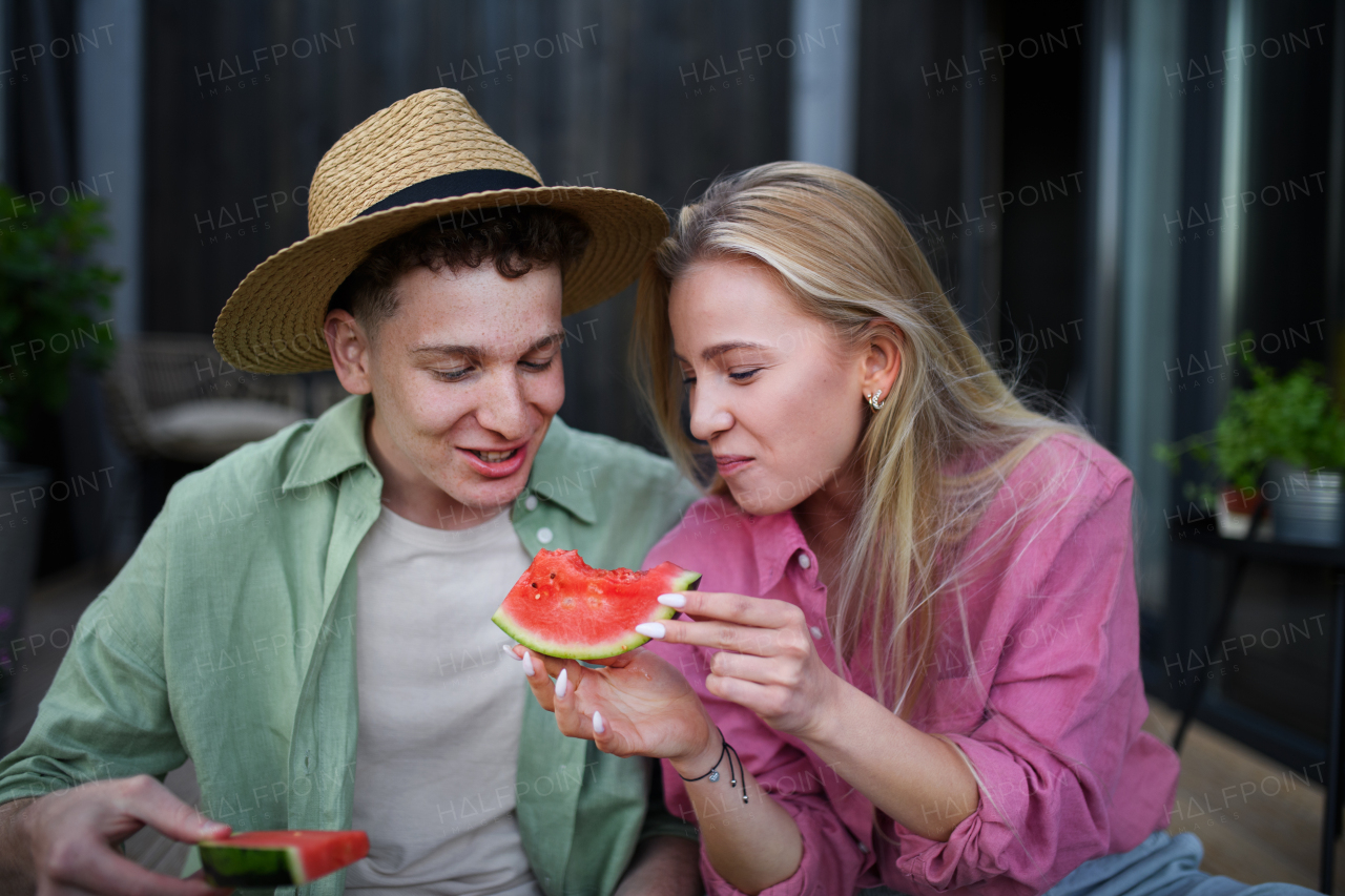 A cheerful young couple in love eating slice of watermelon together