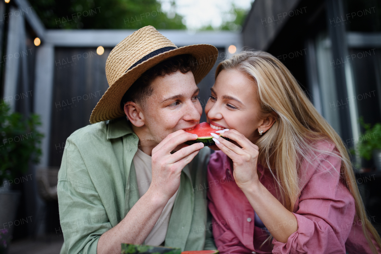 A cheerful young couple in love eating slice of watermelon together