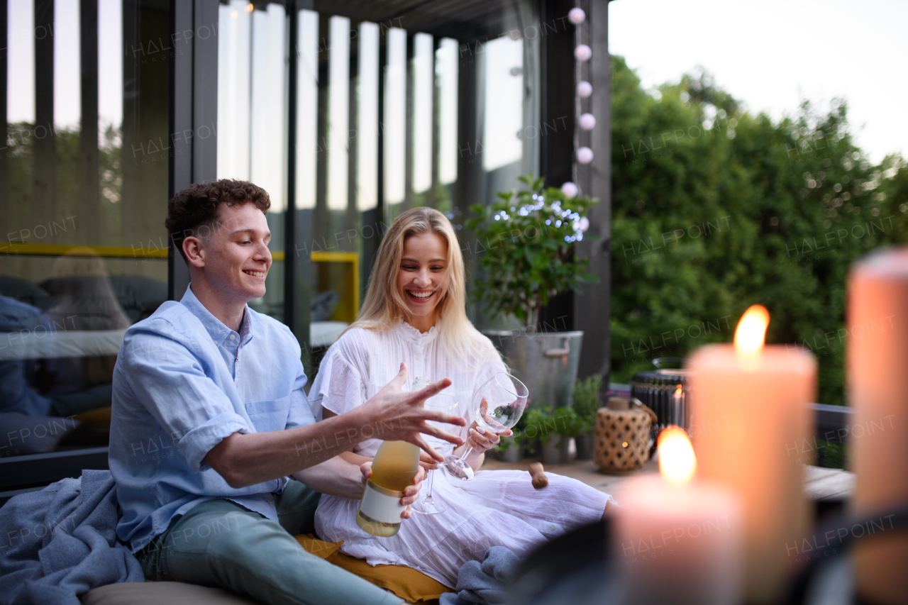 a Young couple opening a bottle of champagne outdoors and celebrating, weekend away in tiny house in countryside, sustainable living.