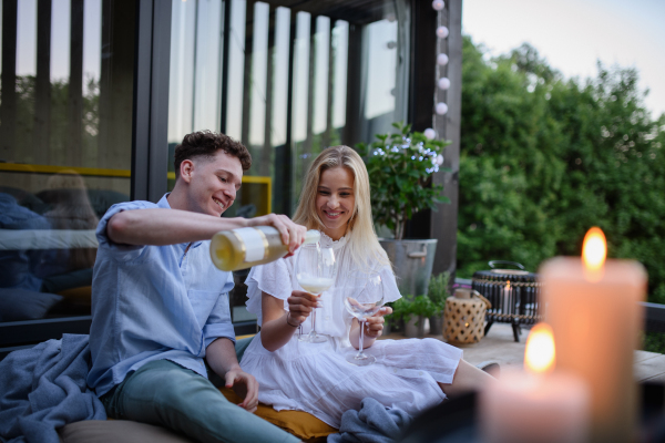 A young couple clinking with wine outdoors, weekend away in tiny house in countryside, sustainable living.