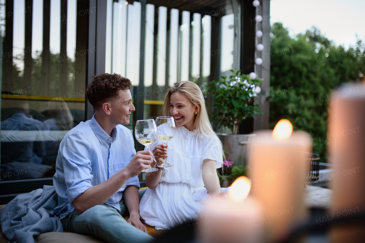 A young couple clinking with wine outdoors, weekend away in tiny house in countryside, sustainable living.