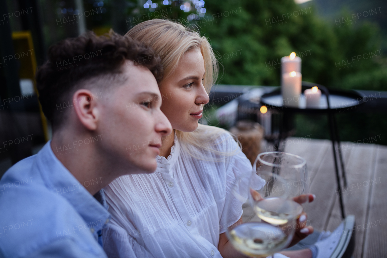 A young couple clinking with wine outdoors, weekend away in tiny house in countryside, sustainable living.