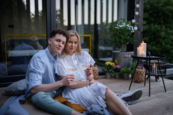 A young couple clinking with wine outdoors, weekend away in tiny house in countryside, sustainable living.