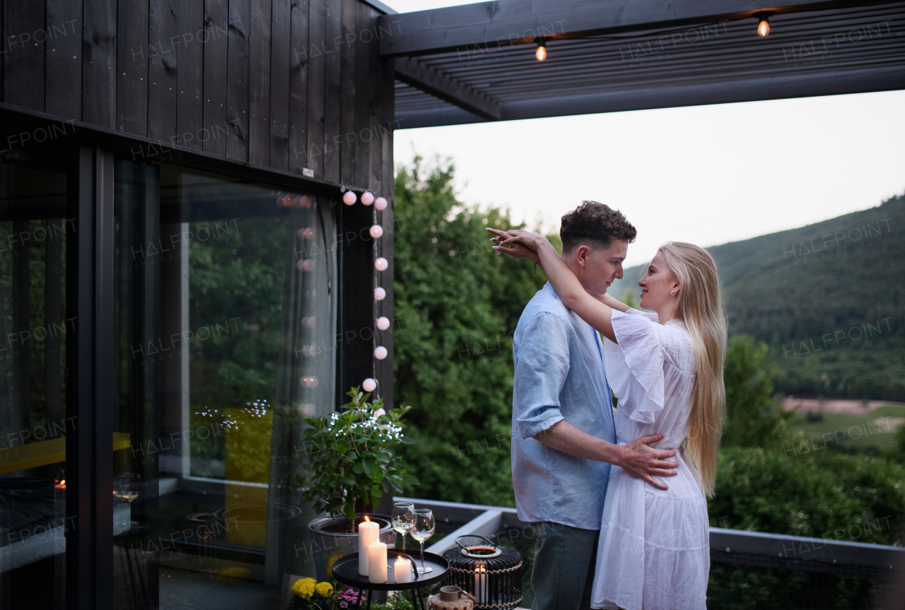 A young couple dancing outdoors, weekend away in tiny house in countryside, travel and holiday concept.