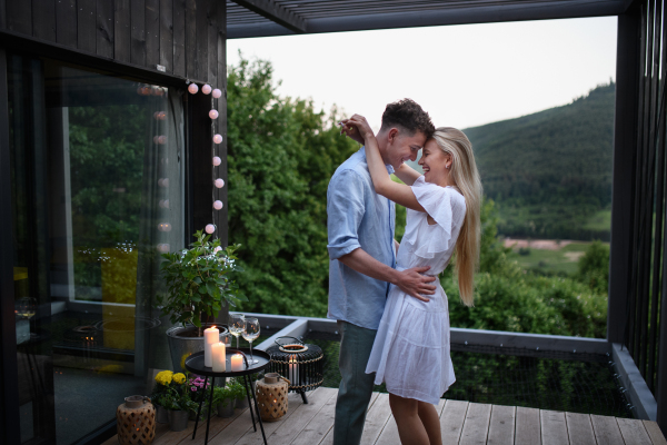 A young couple dancing outdoors, weekend away in tiny house in countryside, travel and holiday concept.