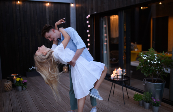 A young couple dancing outdoors, weekend away in tiny house in countryside, travel and holiday concept.