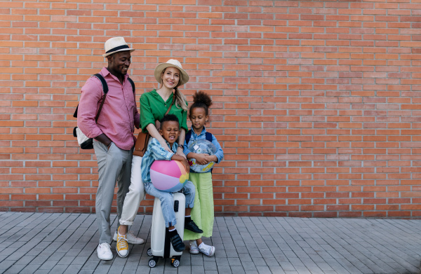 Multiracial family travelling together with small kids. Posing in front of a brick wall.