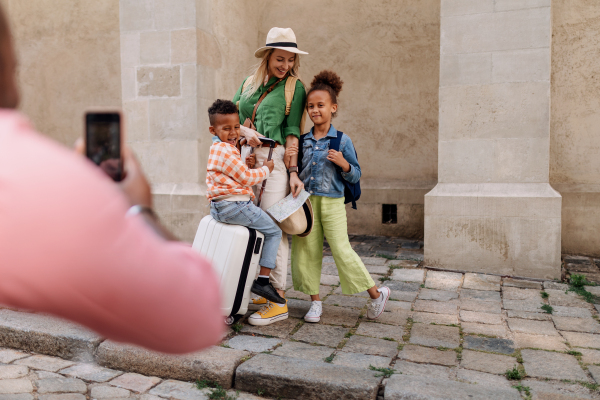 Multiracial family travelling together with small kids. Taking a photo in old city cetre.