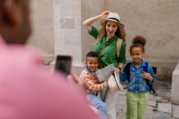 Multiracial family travelling together with small kids. Taking a photo in old city cetre.