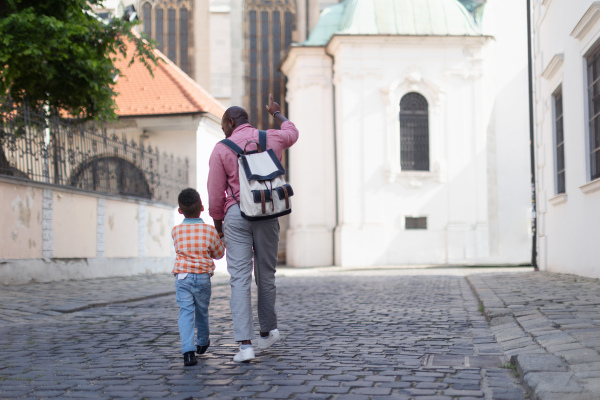 Multiracial father with his small son travelling together, walking in old city centre.