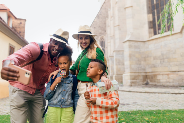 Multiracial family travelling together with small kids. Taking selfiein old city cetre.