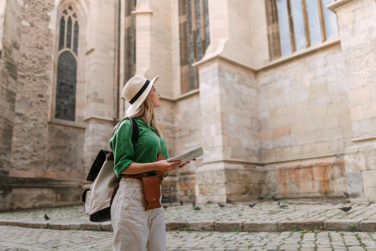 Young blond woman travel alone in old city centre. Wide photography.