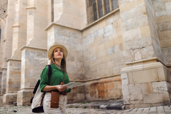 Young blond woman travel alone in old city centre.