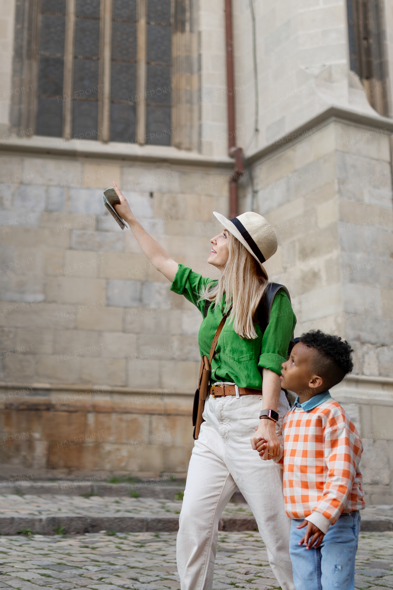 Mother with her small multiracial son travelling together, walking in old city centre.