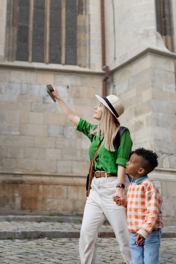 Mother with her small multiracial son travelling together, walking in old city centre.