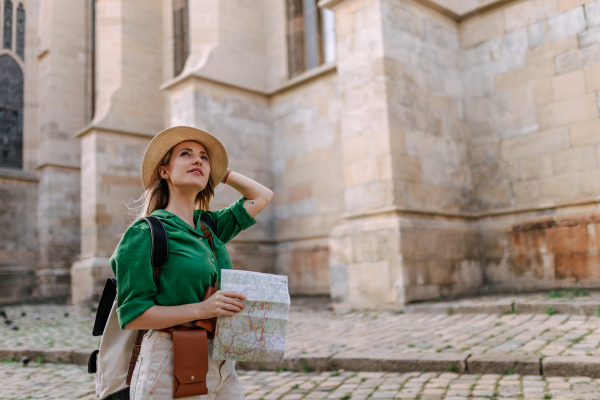 Young blond woman travel alone in old city centre. Wide photography.