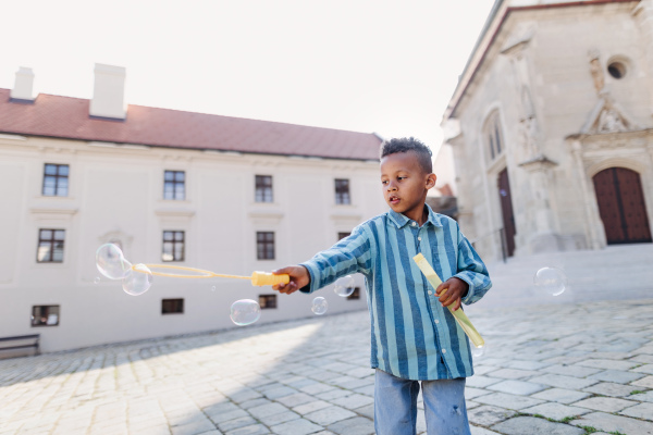 Multiracial boy playing outdoor with a bubble blower.