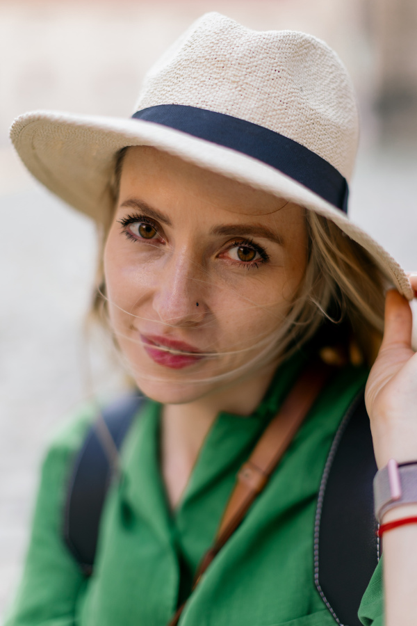 Portrait of a young woman traveler, sitting, resting, smiling and looking at camera.