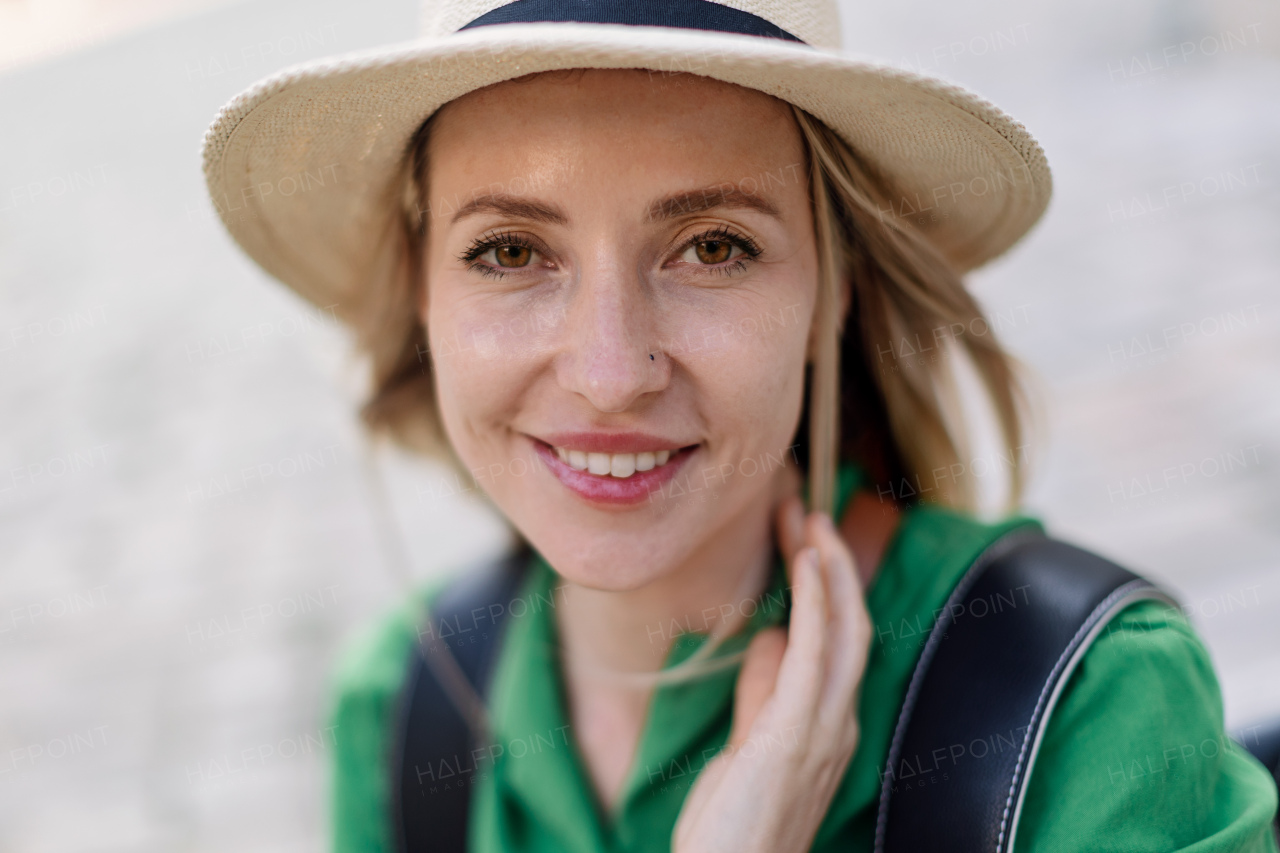 Portrait of a young woman traveler, sitting, resting, smiling and looking at camera.