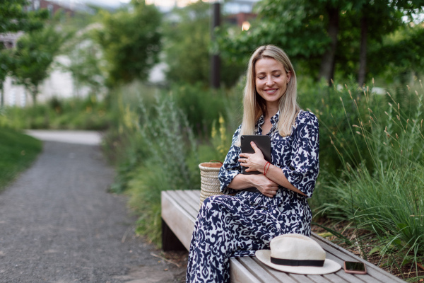 Mature woman sitting in a park bench, enjoying time for herself.