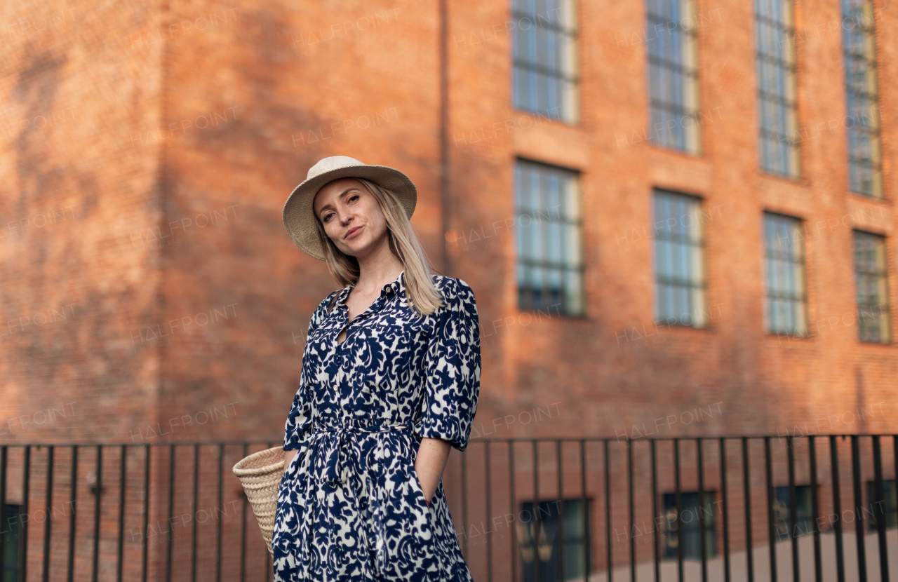 Young woman in a city during sunset, standing and posing in front of old brick building.