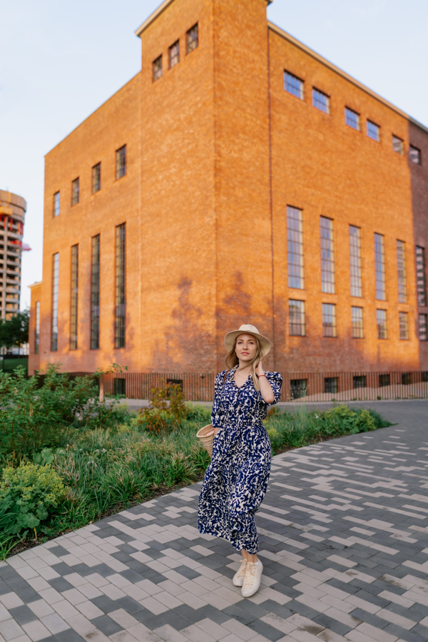 Young woman in a city during sunset, standing and posing in front of old brick building.