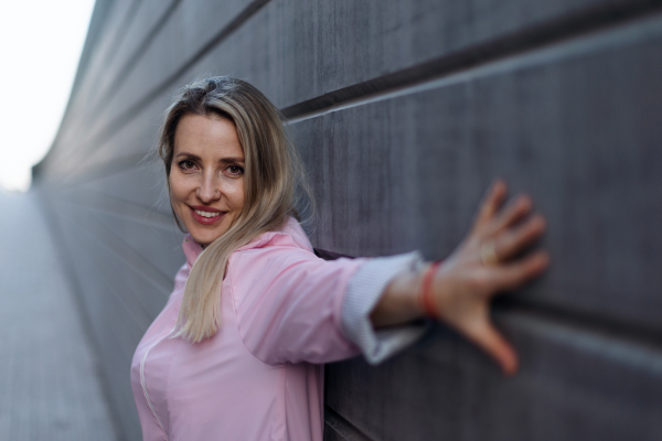 Young blond woman standing in front of a concretewall.