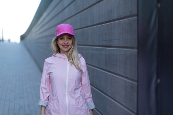 Young woman in a fashion clothes standing in city concrete wall.