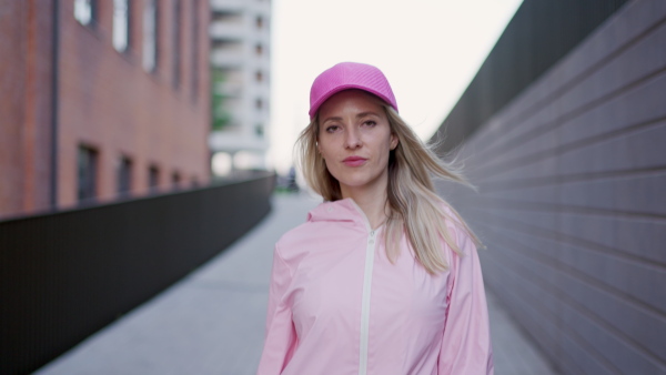 A young happy woman in fashion clothes walking in city concrete wall.