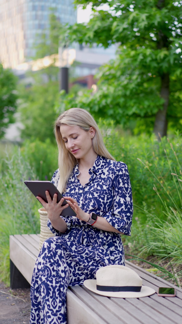 A mid adult woman sitting in park bench in summer, enjoying time for herself.