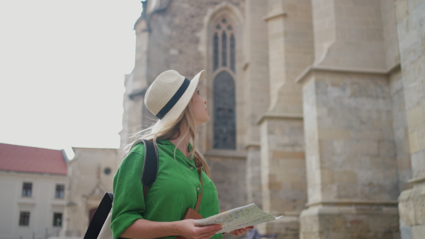 Young blond woman travel alone in old city centre.