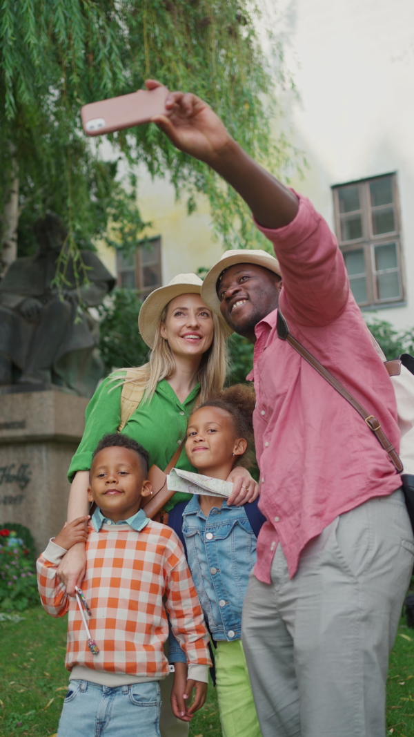 A multiracial family travelling together with small kids. Taking selfie in old city cetre, vertical footage.