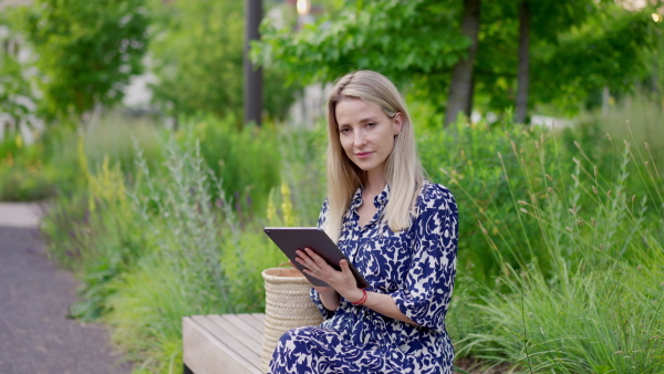 A mid adult woman sitting in park bench in summer, enjoying time for herself.