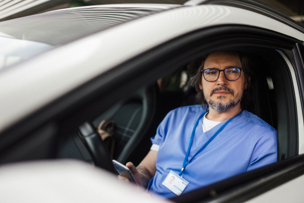 Doctor getting into car, going home from work after long shift. Work-life balance of healthcare worker.