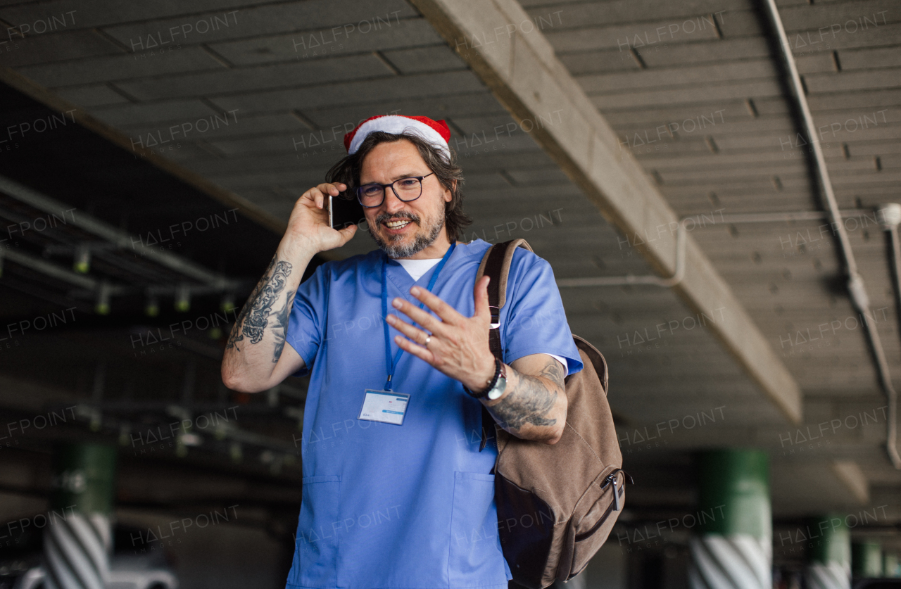 Portrait of male nurse with christmas hat making call. Working in hospital on the Christmas day, Christmas Eve. Doctor working a Christmas shift and can't be with his family.