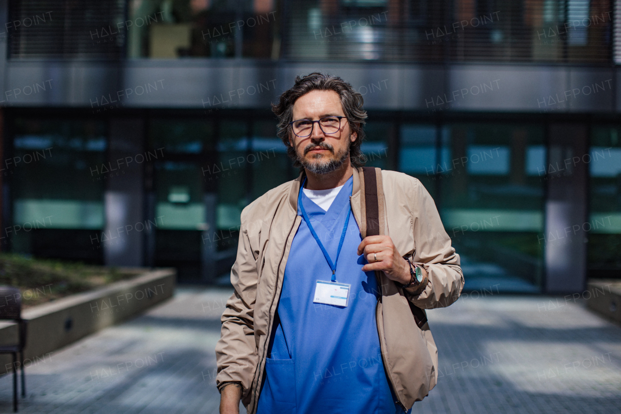 Male doctor in uniform going home from work, looking at camera. Work-life balance of healthcare worker.