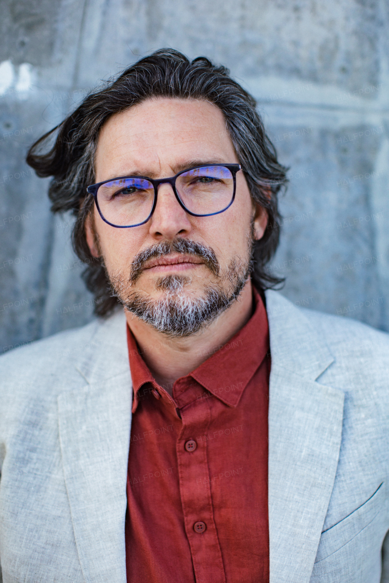 Portrait of mature businessman standing on city street, in front of office building. Handsome man with glasses in a suit.