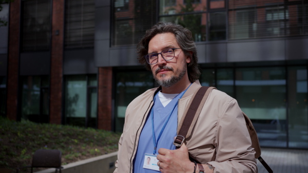 Video of handsome doctor in blue uniform outdoors. Work-life balance of healthcare worker.