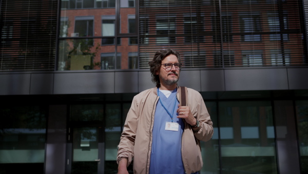 Video of handsome doctor in blue uniform outdoors. Work-life balance of healthcare worker.