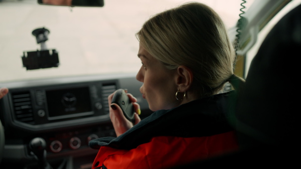 Video of young woman doctor sitting and talking in to walkie-talkie in ambulance car.