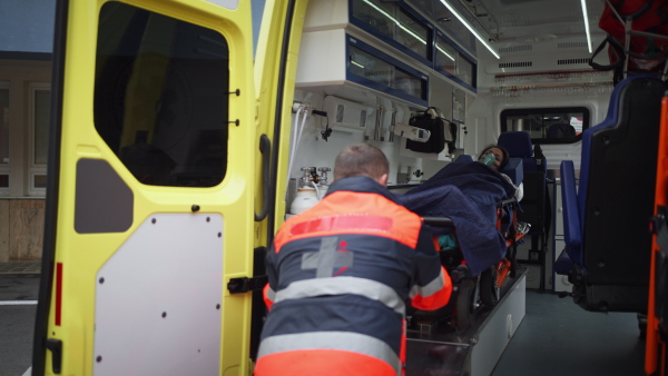 Rescuer taking care of a patient, getting her out from ambulance car.