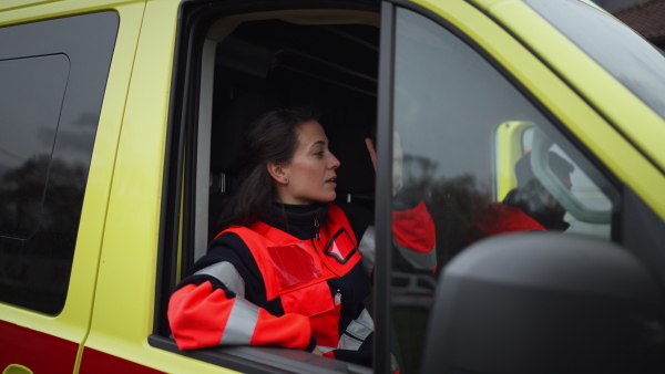 Video of young woman doctor sitting and talking in to walkie-talkie in ambulance car.